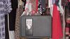 A safe that contains personal assets is sitting among hanging clothes in a closet