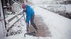 Man shoveling a snow covered sidewalk.