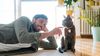 Gentleman on living room floor playing with his cat.