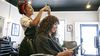 Stylist cutting a woman’s hair in a beauty salon.