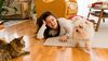 Young lady lying on living room floor playing with her cat and dog.