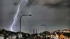 A lightning bolt flashing across the sky over a town.