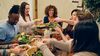 Friends enjoying a Thanksgiving meal, with different multicultural dishes.