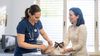 Veterinarian examines a cat while the pet owner assists in holding her cat still.
