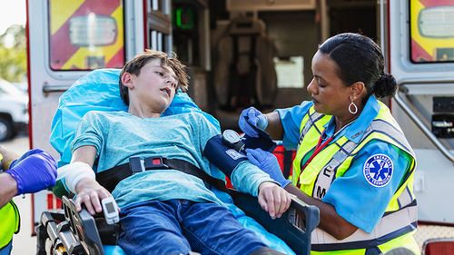 An EMT taking a boy’s blood pressure on a stretcher.