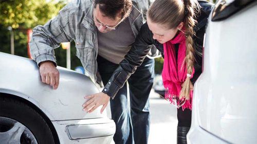 People looking at scratches on a car after a car accident.