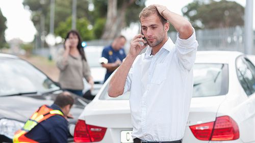 A man and woman calling their agents to see if they have collision insurance after a car accident.