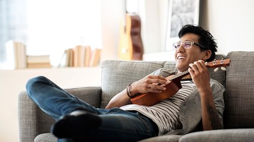 Young man playing a ukelele thinking about how much renters insurance he needs.