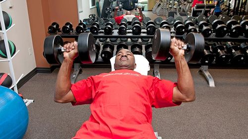 Using his company perks, a man lifts weights at the gym.