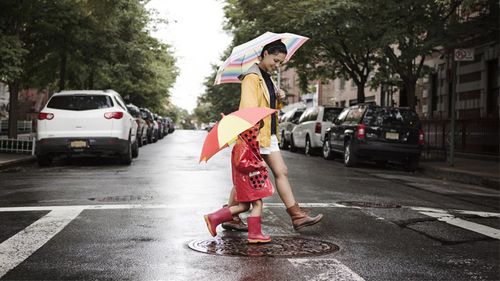 Mother and daughter practice pedestrian safety when crossing the street.