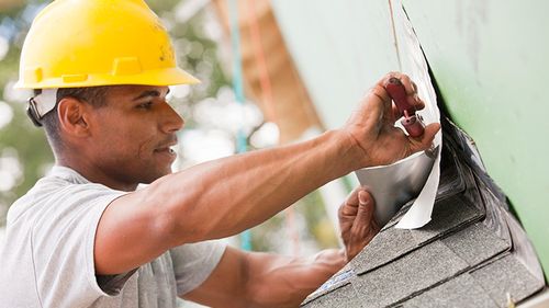 Roofing contractor fitting flashing on a roof.