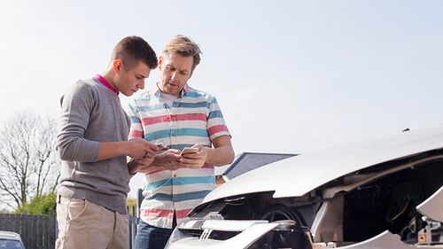 Rideshare driver exchanging insurance information with passenger after an accident.