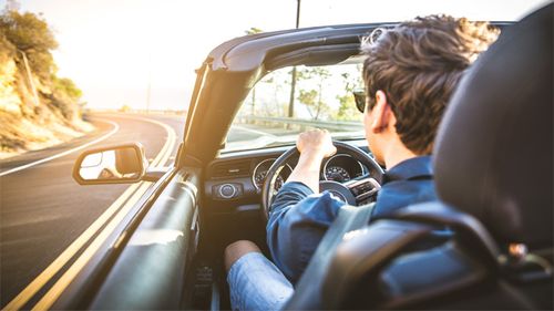 Young man driving a convertible sports car on a summer day.