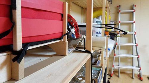 Basement showing items stored on shelves and items leaning against walls.
